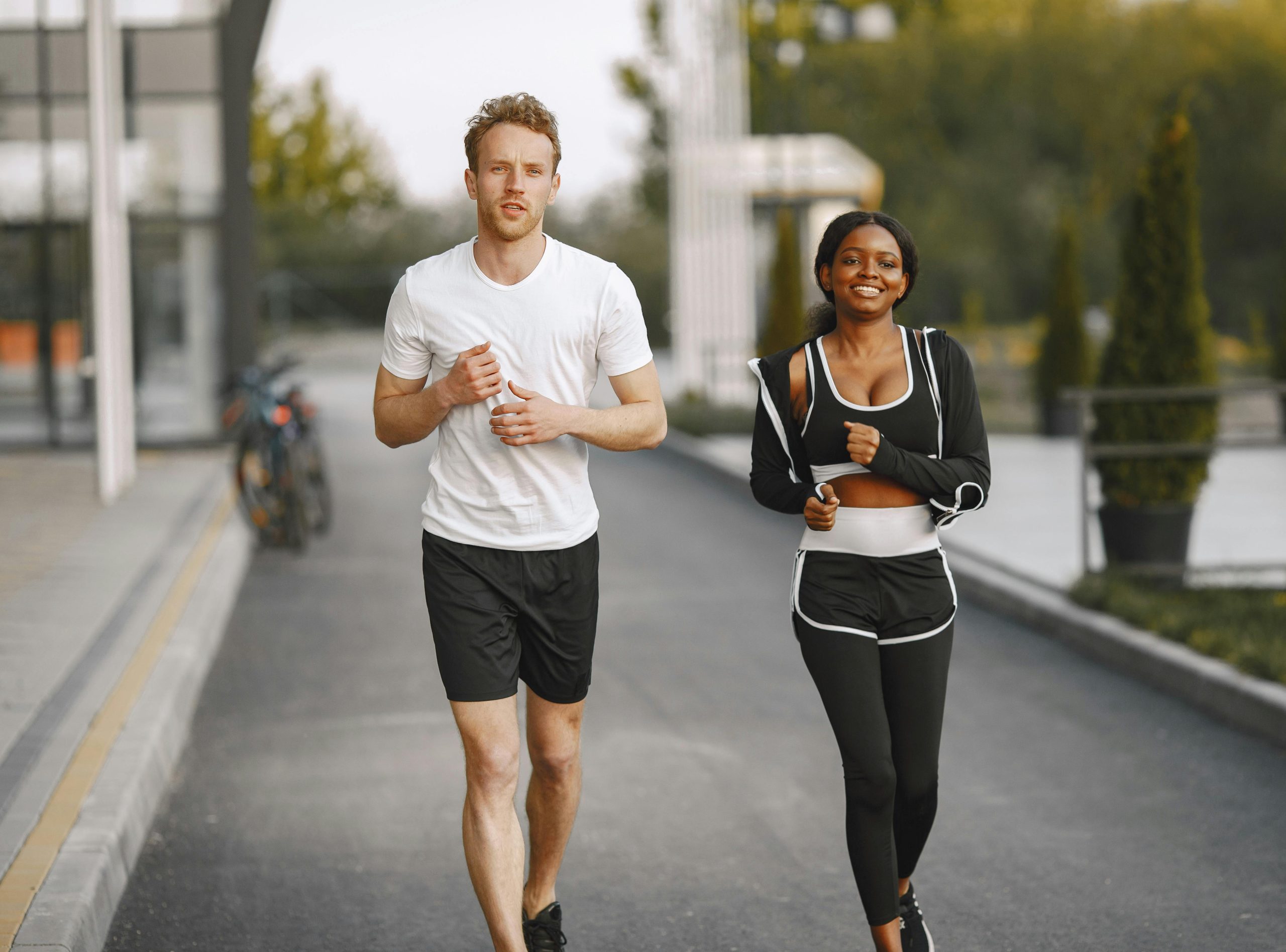 man and woman jogging on a sidewalk